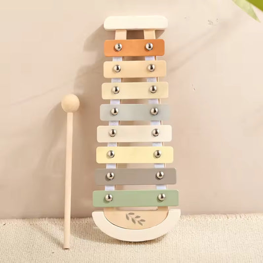 Colorful wooden xylophone with a mallet on a beige background